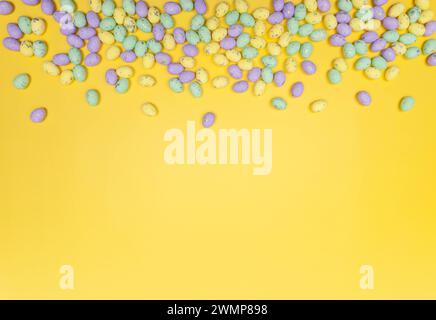 Top view of colourful easter eggs on yellow background. Creative easter composition, spring, copy space, flat lay. Stock Photo