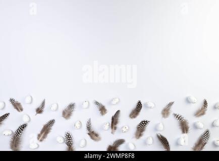 Top view of brown feathers, white easter eggs on white background. Creative easter composition, spring, copy space, flat lay. Stock Photo