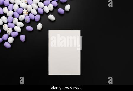 Top view of purple and white easter eggs, white card on black background. Creative easter composition, spring, copy space, flat lay. Stock Photo