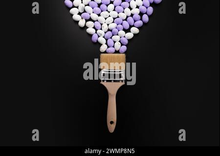 Top view of white and purple easter eggs, paint brush on black background. Creative easter composition, spring, flat lay, copy space. Stock Photo