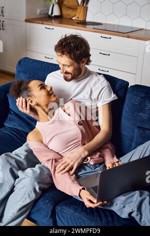 good looking cheerful diverse couple watching movies on their laptop and looking at each other Stock Photo