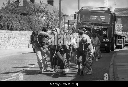 1987, summertime and outside on a road, a group of men taking part in a test of strength, a sponsored lorry pull, Tadcastle, England, UK. Stock Photo
