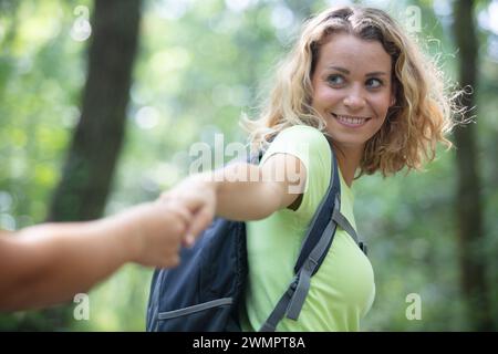 hiker woman holding mans hand and leading him on nature Stock Photo