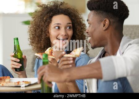 happy relaxed couple sharing pizza and beer at home Stock Photo
