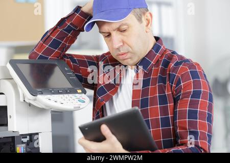 technician using a tablet to fix a printer Stock Photo