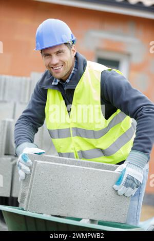 a happy man shifting cement blocks Stock Photo