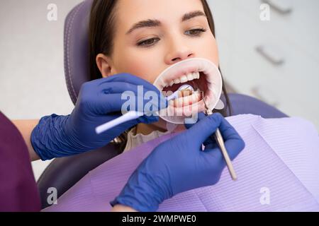 Portrait of young woman in dental clinic. Dentist in rubber gloves doing check up Stock Photo