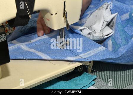 On the subject table with a sewing machine, under the needle is a blue fabric. Stock Photo