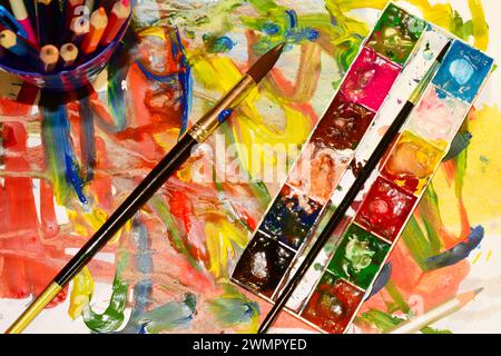 The artist forgot on the table a palette, a brush and watercolors in tubes. Stock Photo