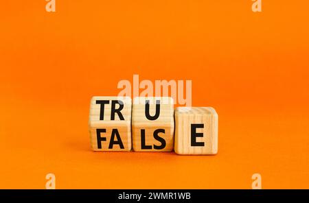 False or true symbol. Turned wooden cubes and changed the word false to true or vice versa. Beautiful orange table, orange background, copy space. Bus Stock Photo