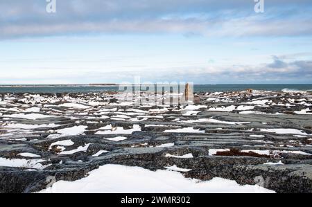 A commemorative marker stands on the site of historic fortifications at Cape Merry battery in Churchill, Manitoba, Canada with Hudson Bay beyond. Stock Photo