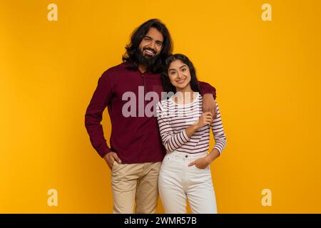 Loving young indian couple embracing on yellow studio background Stock Photo