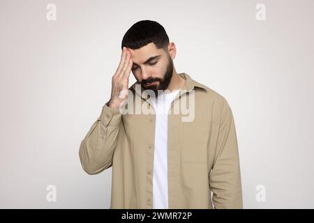 Man with a beard feeling stressed or having a headache, holding his forehead Stock Photo