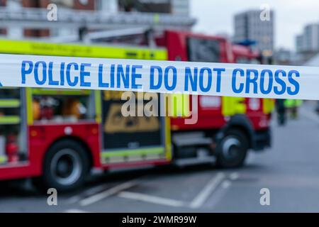 Blue and White POLICE LINE DO NOT CROSS cordon tape with a Fire Engine in the background at the scene of a fire in the UK.  Photo by Amanda Rose/Alamy Stock Photo