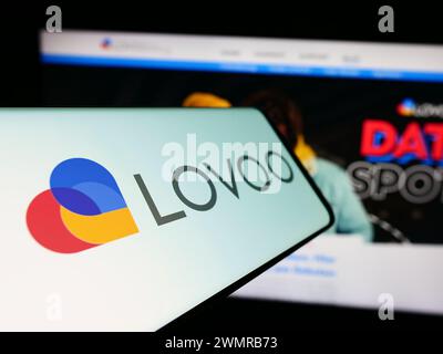 Mobile phone with logo of German online dating platform company LOVOO in front of business website. Focus on left of phone display. Stock Photo