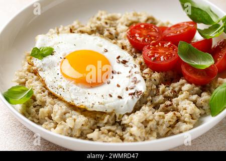 Oatmeal with fried sunny-side-up egg, tomatoes and basil Stock Photo