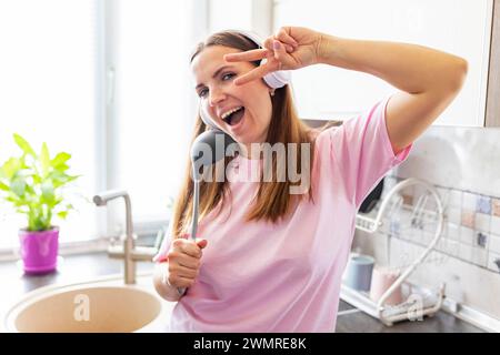 Happy Woman Singing with Kitchen Ladle Stock Photo