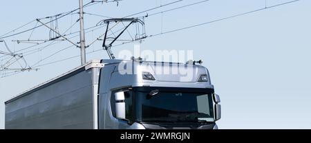 Electric semi truck with pantograph takes energy from wires above the highway. Stock Photo