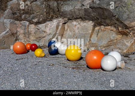 Plastic buoys laying on the shore in the sunshine. Rocks in background Stock Photo