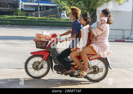 SAMUT PRAKAN, THAILAND, DEC 05 2023, A group of people with a sleeping baby ride together on a motorbike Stock Photo