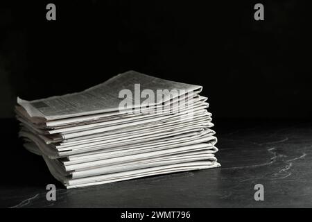 Stack of newspapers on dark stone table. Journalist's work Stock Photo