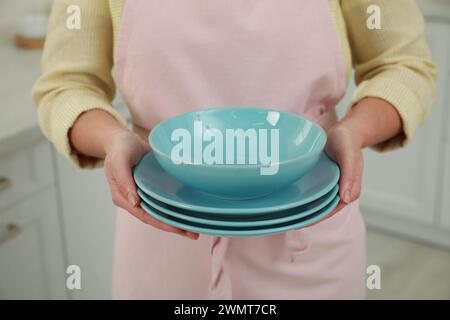 Woman holding plates in kitchen, closeup view Stock Photo
