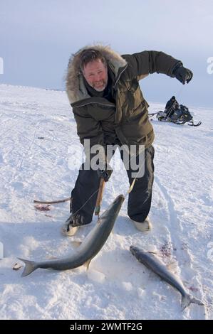 Tim Cook Alaskan guide ice fishing for sheefish on Kotzebue sound outside the village town of Kotzebue Sound Northwestern arctic Alaska Stock Photo