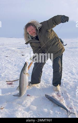 Tim Cook Alaskan guide ice fishing for sheefish on Kotzebue sound outside the village town of Kotzebue Sound Northwestern arctic Alaska Stock Photo