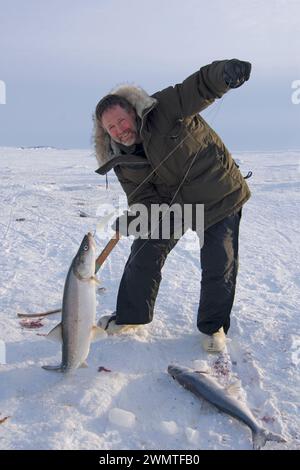 Tim Cook Alaskan guide ice fishing for sheefish on Kotzebue sound outside the village town of Kotzebue Sound Northwestern arctic Alaska Stock Photo