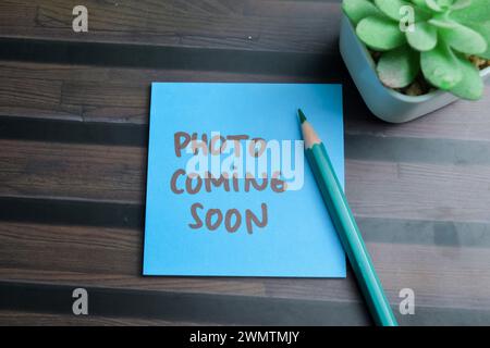 Concept of Photo Coming Soon write on sticky notes isolated on Wooden Table. Stock Photo