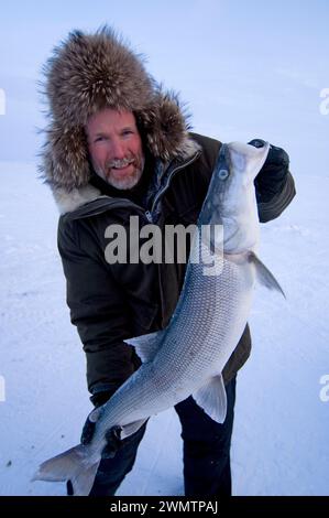 Tim Cook Alaskan guide ice fishing for sheefish on Kotzebue sound outside the village town of Kotzebue Sound Northwestern arctic Alaska Stock Photo