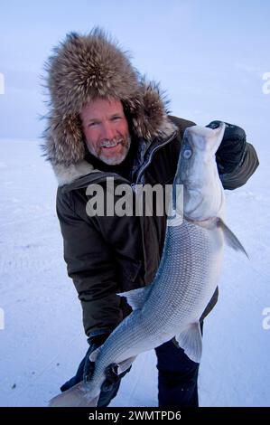 Tim Cook Alaskan guide ice fishing for sheefish on Kotzebue sound outside the village town of Kotzebue Sound Northwestern arctic Alaska Stock Photo