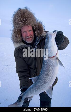 Tim Cook Alaskan guide ice fishing for sheefish on Kotzebue sound outside the village town of Kotzebue Sound Northwestern arctic Alaska Stock Photo