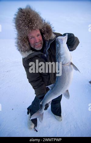 Tim Cook Alaskan guide ice fishing for sheefish on Kotzebue sound outside the village town of Kotzebue Sound Northwestern arctic Alaska Stock Photo