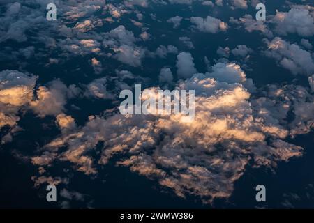 Beautiful sunset sky above clouds with dramatic light. Cabin view from airplane. Stock Photo