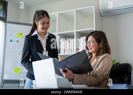 Happy two business woman account discussing documents financial result project overview at office meeting, Executives and employee holding tax papers Stock Photo