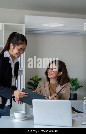 Happy two business woman account discussing documents financial result project overview at office meeting, Executives and employee holding tax papers Stock Photo
