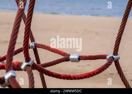 Red rope sections fastened with a metal clamp on a background of brown ...
