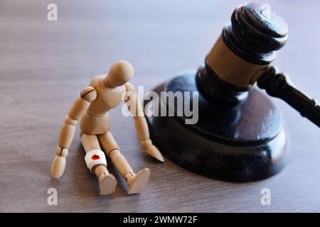 Bandage wrap with blood stain, wooden doll and judge gavel. Personal injury law concept. Stock Photo