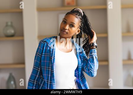 A young African American woman poses confidently, hand in her braided hair Stock Photo