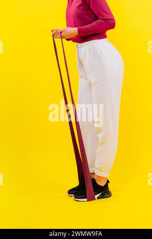 Sports woman in fashion sportswear exercising with elastic band in studio Stock Photo