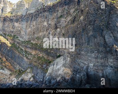 Weathered seaside rock face texture. Aged volcanic stone wall surface background pattern with cracks and scratches. Ischia Island, Italy. Stock Photo