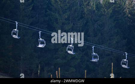 Altastenberg, Germany. 27th Feb, 2024. The gondolas of a ski lift in the village near Winterberg in the Hochsauerland region hang on their cable above the ski slope without snow. Credit: Robert Michael/dpa/Alamy Live News Stock Photo