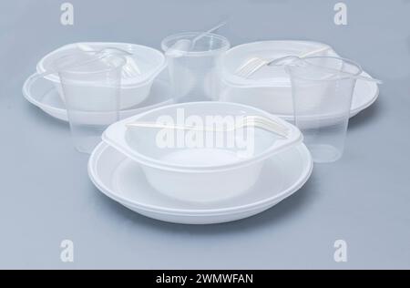 Various white plastic disposable tableware on blue background. Stock Photo