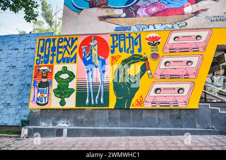 A cool, hip mural on a wall with graphics of cassettes, a tall camel, pure joy spray, a flower, a peace sign. In Almaty, Kazakhstan. Stock Photo