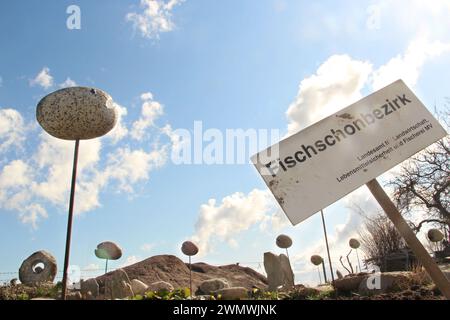 Sign on german 'fish conservancy area' with sculptures of stone fish around. Stock Photo