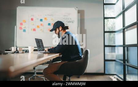 Focused young professional codes in a modern office. This tech company worker is a software designer and web developer, contributing to innovative pro Stock Photo