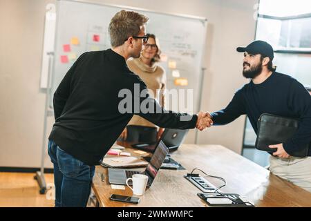 Two software developers shaking hands to solidify a deal on a software development project. Business professionals engaging in a productive meeting fo Stock Photo