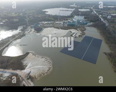 Aerial drone view on a floating solar panel park next to a large industrial factory complex and sand extraction site. Belgium, Europe. Stock Photo