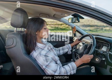 Portrait of a young woman sitting in a car and  holding on to the steering wheel. Buy your first car concept Stock Photo